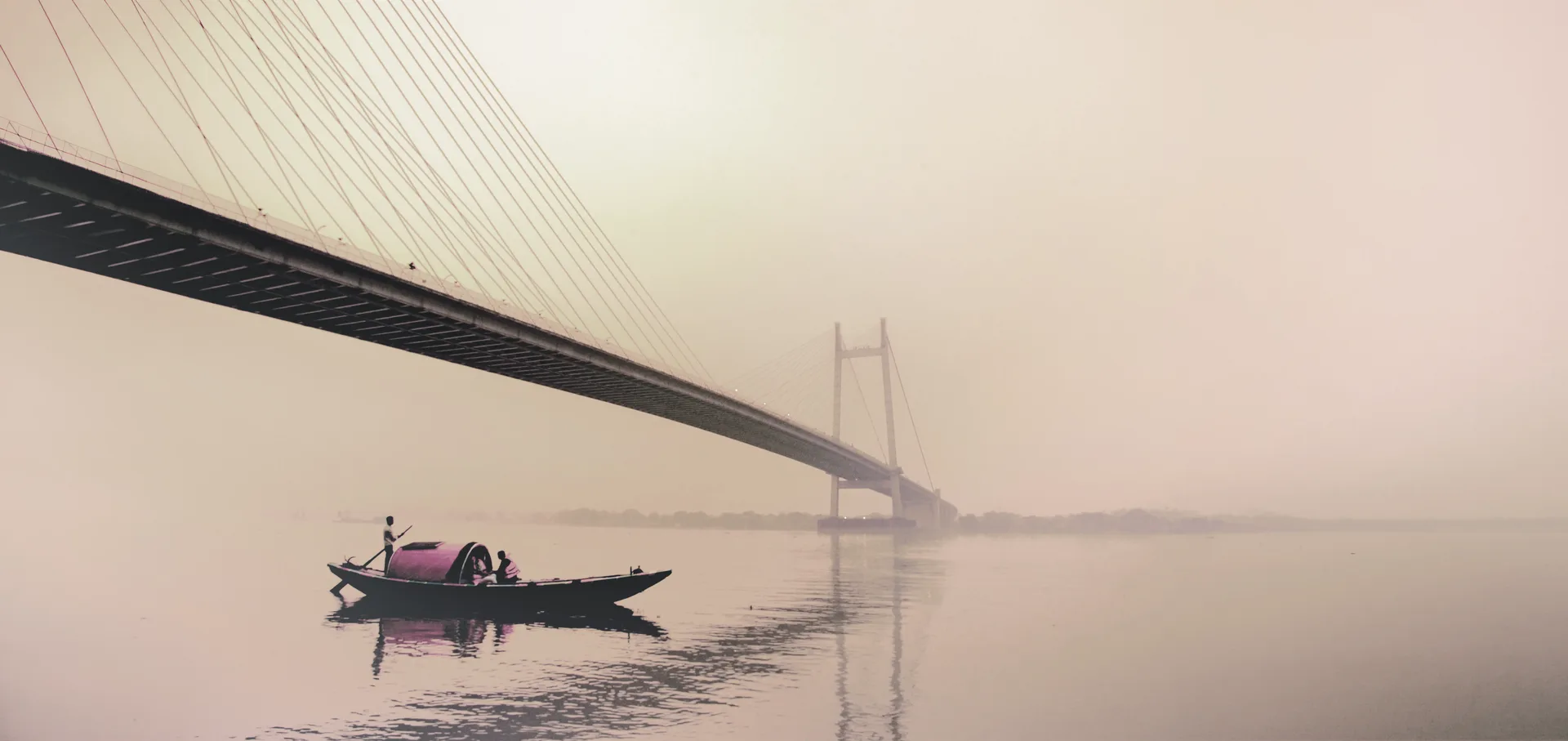 Vidyasagar Setu from beneath, a single boat on the misty Hooghly